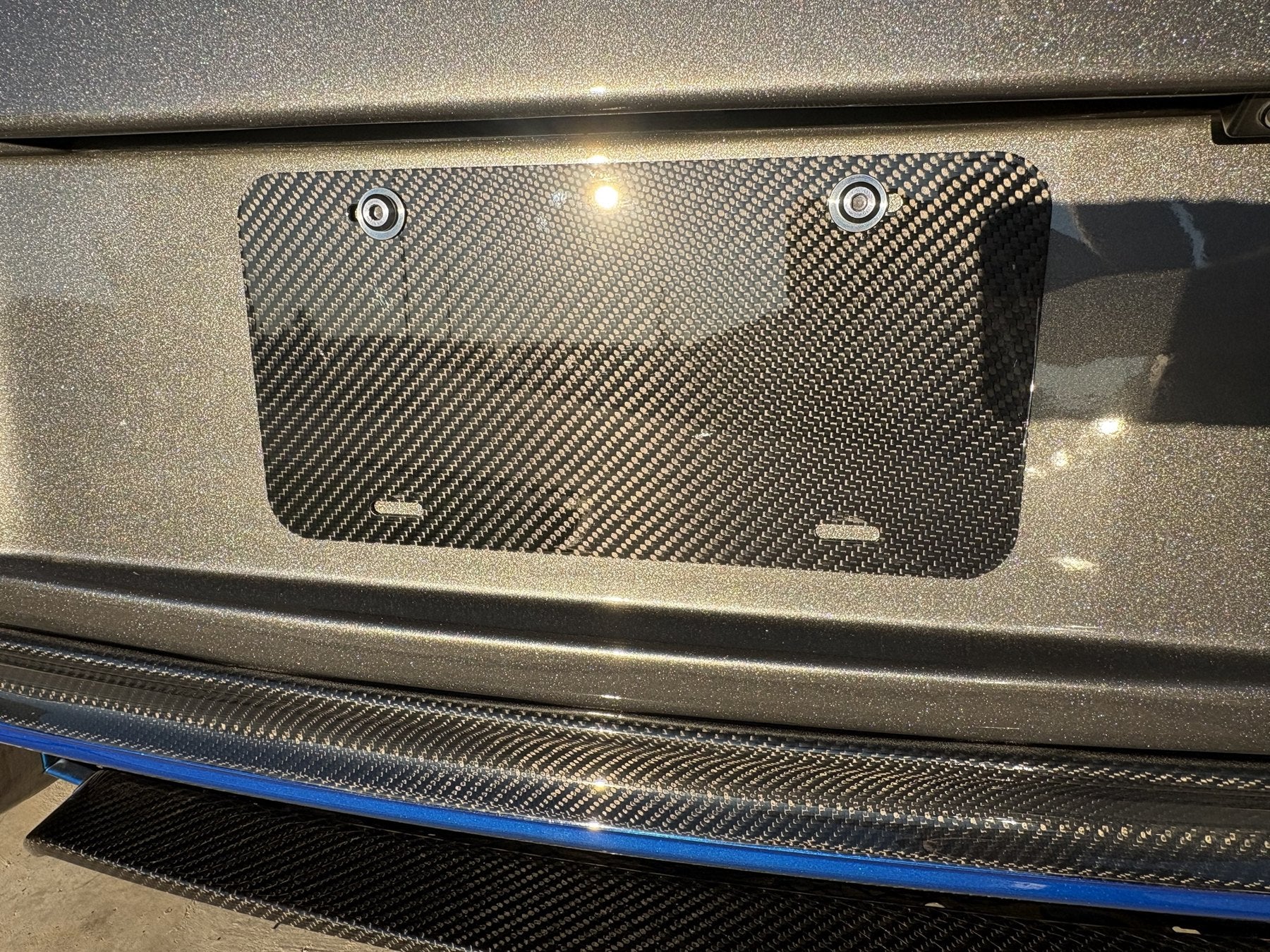Carbon fiber plate mounted on a car above a carbon fiber bumper lip